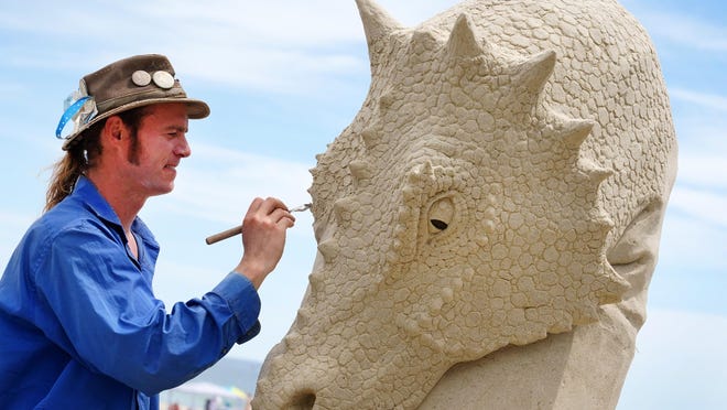 Master sculptor Abe Waterman adds detail to a dragon on a preview sand sculpture along Hampton Beach, reminding beachgoers that the annual Hampton Beach Sand Sculpting Classic will take place Sept. 3-5.