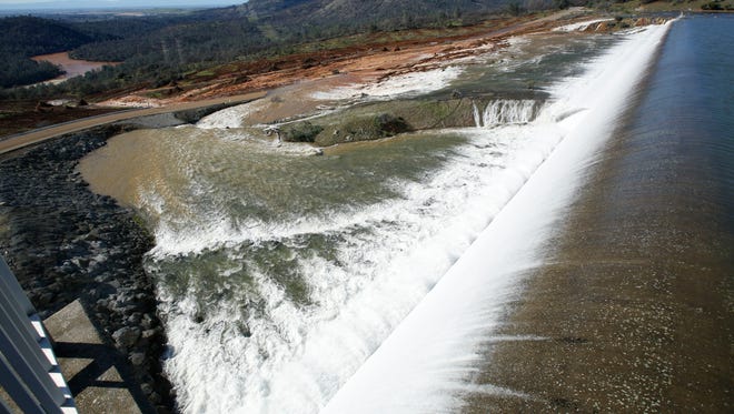 Water flows over the emergency spillway at Oroville Dam on Saturday in Oroville. Water started flowing over the emergency spillway at the nation's tallest dam for the first time after erosion damaged the Northern California dam's main spillway