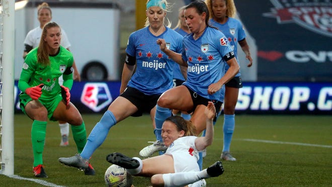 Reign's Kristen McNabb, foreground, kicks the ball as Chicago Red Stars' Julie Ertz, center, and Vanessa DiBernardo, right, defend during the first half of an NWSL Challenge Cup soccer match at Zions Bank Stadium, Saturday, July 18, 2020, in Herriman, Utah. (AP Photo/Rick Bowmer)