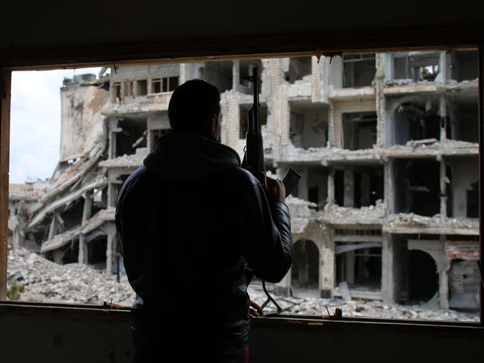 A Syrian rebel fighter stands behind a window in a