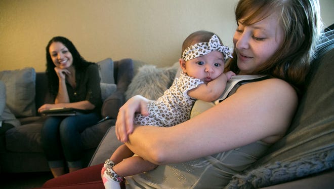 Breanna Donaldson, a recovering heroin addict, holds 3-month-old daughter Mazie as she meets with Brianna Wiseman, a family support specialist with Southwest Human Development, at Donaldson's home in Scottsdale on Nov. 28, 2017.