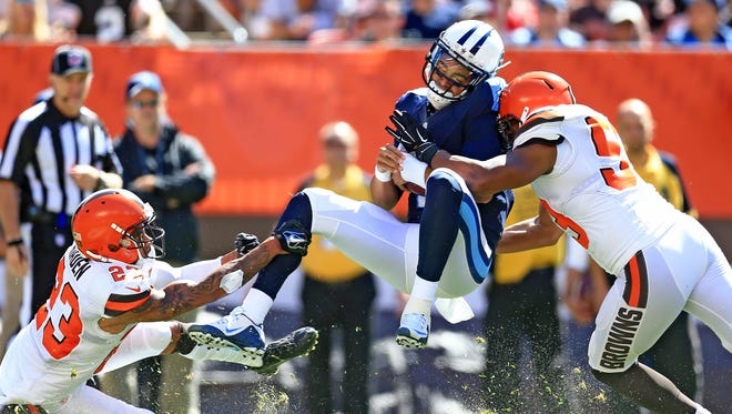 Titans quarterback Marcus Mariota (8) is tackled by Browns cornerback Joe Haden (23) and inside linebacker Craig Robertson (53) during the first quarter.