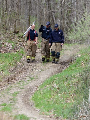 Lancaster firefighters walk down an access road at Alley Park after helping to free man who got stuck in a swampy area of the park while hunting mushrooms Wednesday in Berne Township. The man, Dave Waters, wasn't injured in the incident.