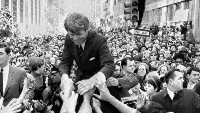 In this April 2, 1968 file photo U.S. Sen. Robert F. Kennedy, D-NY, shakes hands with people in a crowd while campaigning for the Democratic party's presidential nomination on a street corner, in Philadelphia.