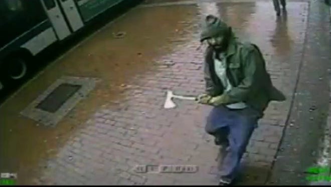In this frame grab taken from video provided by the New York Police Department, an unidentified man approaches New York City police officers with a hatchet, Thursday, Oct. 23, 2014, in the Queens borough of New York. The man injured two with the hatchet before the other officers shot and killed him, police said.