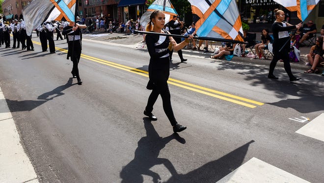 The flags of the St. Cloud Solar Sound Marching Band perform for the crowd during the 2018 Granite City Days Parade in St. Cloud.