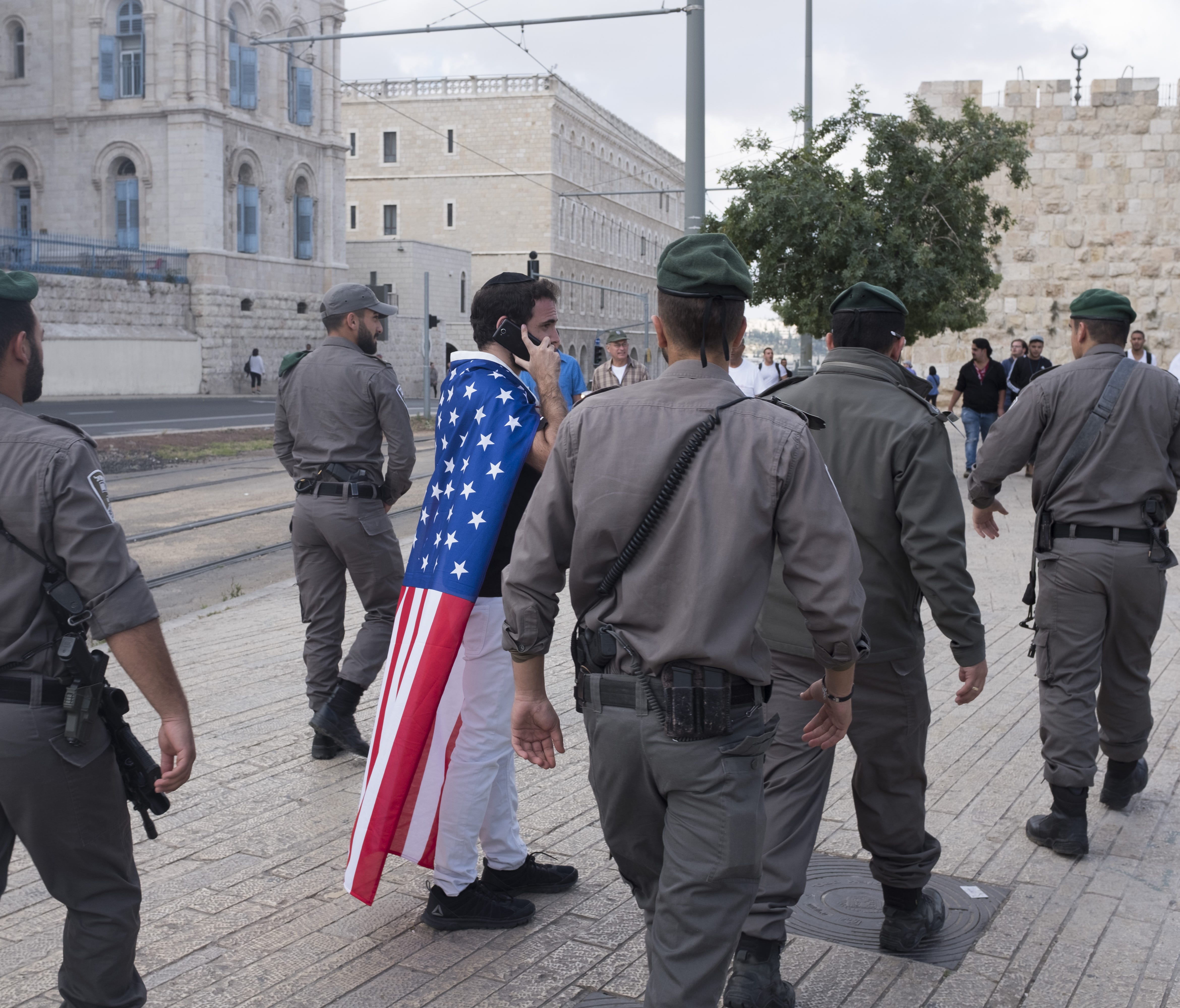 Israeli border policemen walk next to a man wearing an American flag outside the Old City on May 13, 2018 in Jerusalem, Israel. Israel mark Jerusalem Day celebrations  the 51th anniversary of its capture of Arab east Jerusalem in the Six Day War of 1