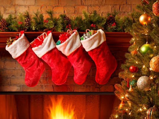 Christmas stockings hanging from a mantelpiece above glowing fireplace