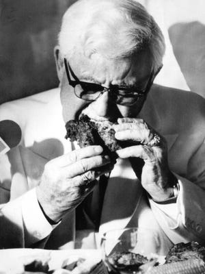 Col. Harland Sanders bit into a piece of his famous recipe chicken as he celebrated his 86th birthday at the 21 Club in New York. Sept. 9, 1976