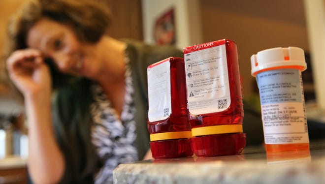 Shelley Ewalt sits in her home, in Princeton, N.J., near an amber-colored CVS pharmacy prescription bottle, right, and two uniquely designed red ones from Target. After CVS took over operation of Target's drugstores earlier this year, distraught customers have been asking the drugstore chain to bring back the retailer’s red prescription bottles, which came with color-coded rings, labeling on the top and prescription information that was easier to read. Ewalt tweeted to the drugstore chain, asking if there was any chance they might return to the design of the Target bottles, which she found easier to open.