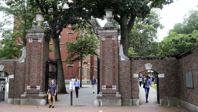 In this Aug. 13, 2019, file photo, pedestrians walk through the gates of Harvard Yard at Harvard University in Cambridge. Harvard and the Massachusetts Institute of Technology filed a federal lawsuit Wednesday, challenging the Trump administration's decision to bar international students from staying in the U.S. if they take classes entirely online this fall. Some institutions, including Harvard, have announced that all instruction will be offered remotely in the fall during the ongoing coronavirus pandemic.