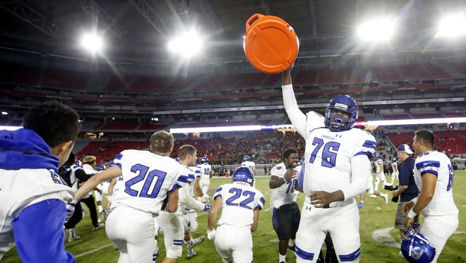 Chandler offensive lineman T'ziah Moore celebrates defeating Mountain Pointe by dumping head coach Shaun Aguano in ice water during the 6A Conference state championship game at University of Phoenix Stadium in Glendale.