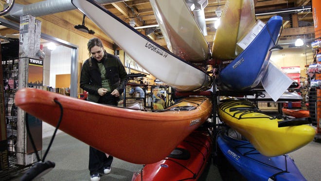 In this March 13, 2006, file photo, a woman looks over sea kayaks as she shops for a birthday present for herself at an REI store in Seattle. Outdoor retailer REI said Thursday, March 1, 2018, that it's halting future orders of some popular brands - including CamelBak water carriers, Giro helmets and Camp Chef stoves - whose parent company also makes ammunition and assault-style rifles.