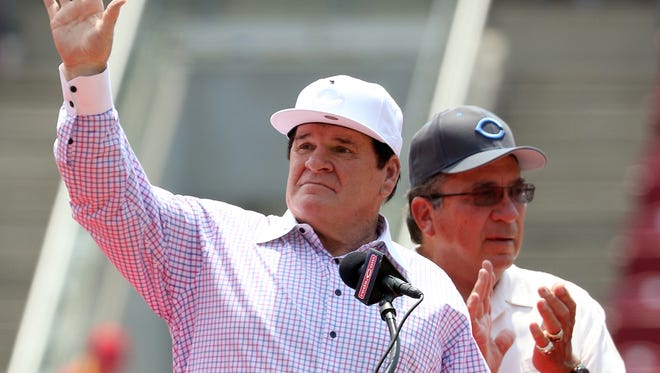 Former Reds great Pete Rose waves to the crowd as former teammate Johnny Bench applauds during Sunday's ceremony to retire Rose's number 14.