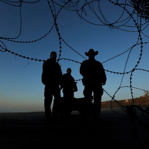Border patrol officers stand at the beach on the...