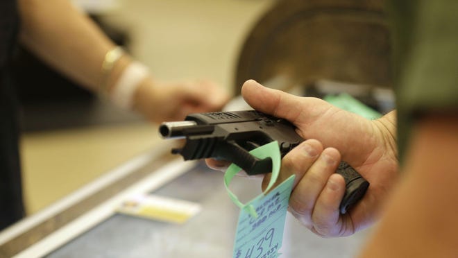 A worker shows a customer a gun on June 17 at Maxon Shooter's Supplies and Indoor Range in Des Plaines.