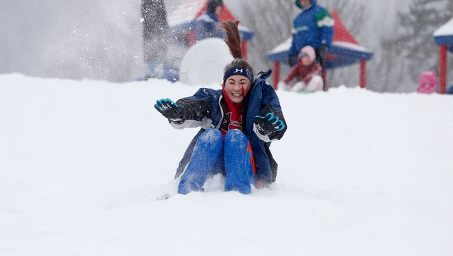 Children and adults sled down the hill at Cohen Elementary School in Elmira Heights on March 15.
