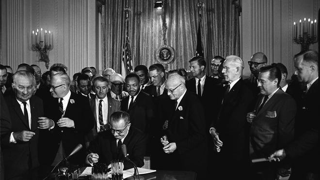
President Lyndon Johnson signed the Civil Rights Act of 1964 into law on July 2, with Martin Luther King, Jr., looking on. 
