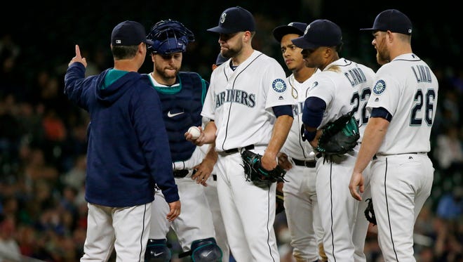 Seattle Mariners manager Scott Servais, left, signals for left-handed pitcher Mike Montgomery to come into the game and relieve starting pitcher Nathan Karns, center, during the fifth inning of a baseball game against the Cleveland Indians, Thursday, June 9, 2016, in Seattle.