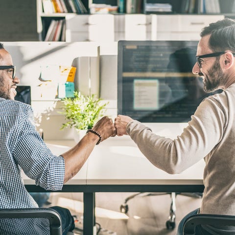 Two co-workers fist bump each other in happy celeb