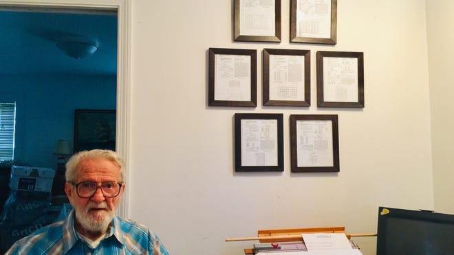 John Corcoran beside seven of his framed patents in his Hyannis Port home office.