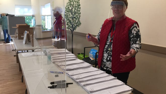 Barnstable Town Clerk Ann Quirk dons a face shield from behind a plexiglass barrier during early voting at the Adult Community Center. Only one more day of early in-person voting, people! Take an umbrella! Open at 8:30 a.m. to 5 p.m. Friday. Polling stations open Tuesday 8-7.