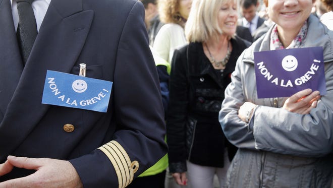 A pilot and Air France workers gather in front of the company headquarters as they demonstrate against the pilots strike, in Roissy, outside Paris, Sept. 24, 2014.