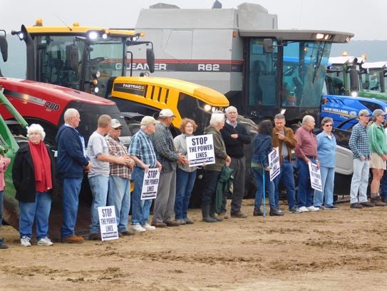 About 40 people lined up in front of farm equipment