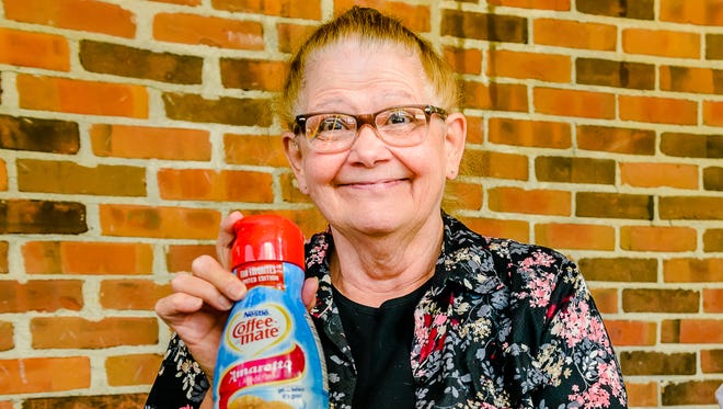 Williamston resident Judy Riedel Tugen holds a bottle of Amaretto Coffee-mate at a surprise gathering at Harrison Roadhouse in East Lansing. The company is bringing Tugen's favorite flavor back through the end of the year.