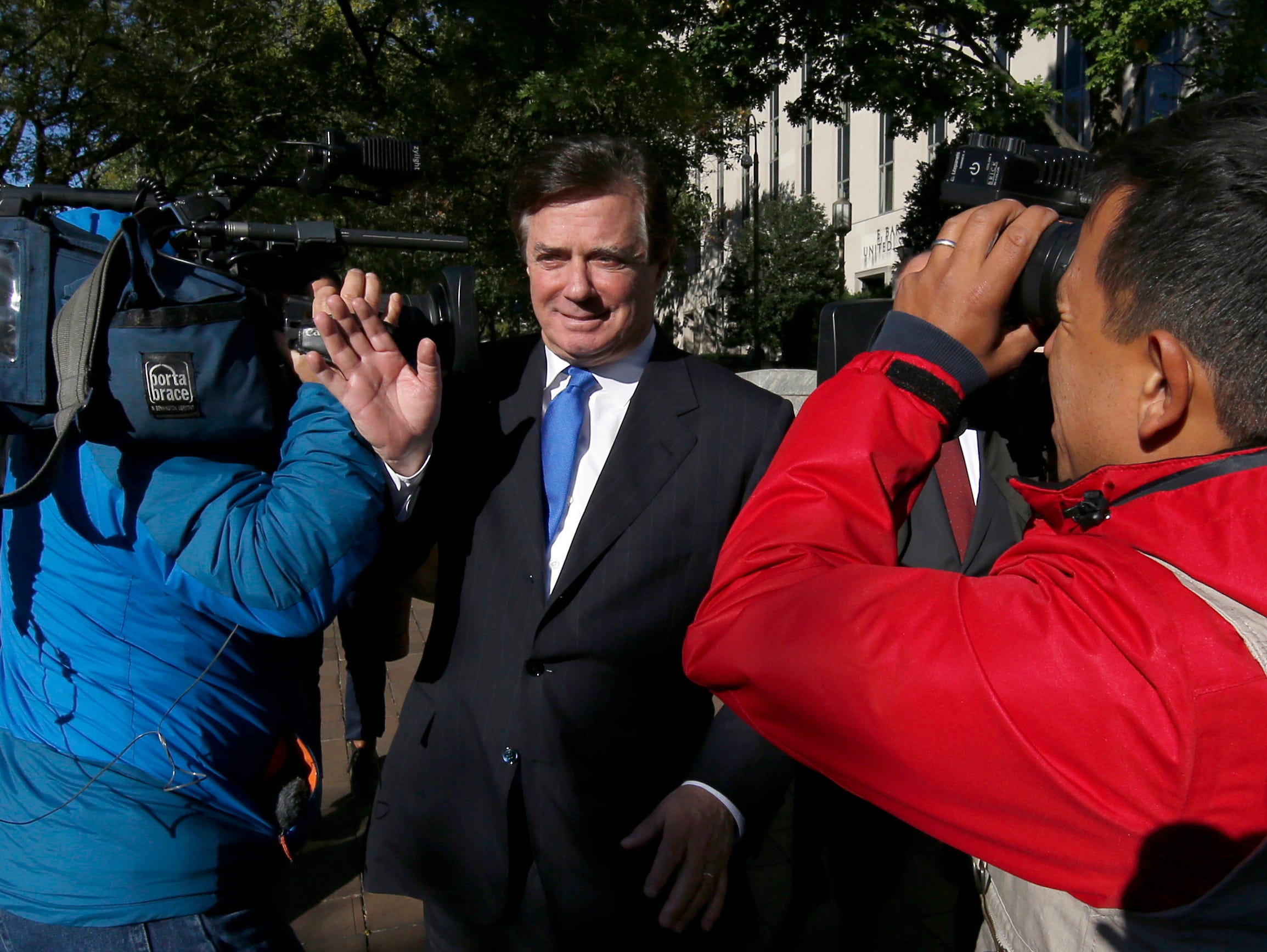 Manafort makes his way through television cameras as