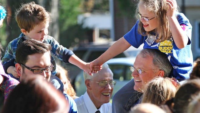 Kaydon Smith, left, on the shoulders of R.J. Smith of Anderson, holds hands with Michaela Kinard, on the shoulders of her father Michael Kinard of Anderson, during the Buddy Walk event at Anderson University in October 2014.