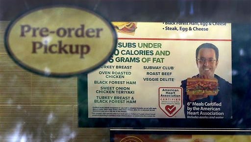 A photo of Subway restaurant spokesman Jared Fogle is seen on a menu board hanging inside one of its locations Tuesday, July 7, 2015, in St. Louis. FBI agents and Indiana State Police raided the home of Fogle on Tuesday, removing electronics from the property and searching the house with a police dog. (AP Photo/Jeff Roberson)