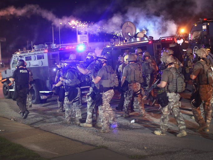 Police advance while sending a volley of tear gas toward demonstrators protesting the killing of teenager Michael Brown on Sunday in Ferguson, Mo.