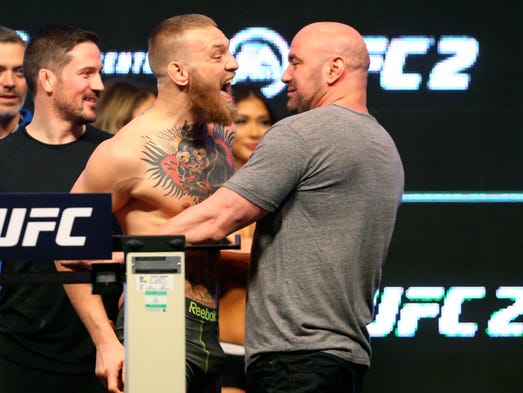 Conor McGregor (left) is held back by UFC president