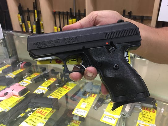 A pawn-shop employee displays a Hi-Point 9mm, the same