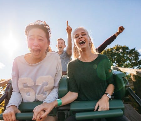 Young adults smiling while riding a roller coaster.