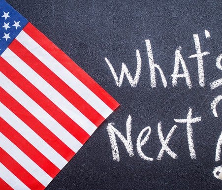 What's Next? written on chalkboard next to an American flag.