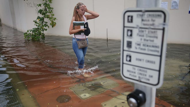 Yana Kibyakova walks through a flooded street that was caused by the combination of the lunar orbit, which caused seasonal high tides, and what many believe is the rising sea levels due to climate change on Sept. 29, 2015 in Miami Beach, Fla.