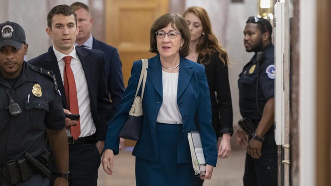 Sen. Susan Collins, R-Maine, is escorted by U.S. Capitol Police as she is met by cameras and reporters asking about embattled Supreme Court nominee Brett Kavanaugh, on Capitol Hill in Washington, Wednesday, Oct. 3, 2018. Collins was arriving to chair the Senate Special Committee on Aging. (AP Photo/J. Scott Applewhite)