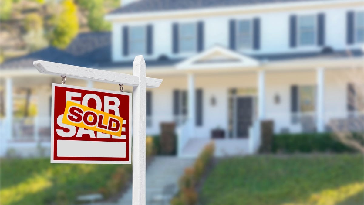 A "for sale" sign with "sold" sticker in front of a home.