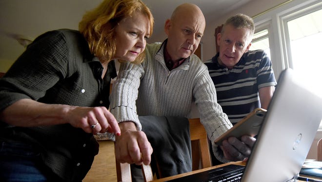 Siblings Janet McMillan, Duncan Livingstone and Tommy Livingstone enjoy looking at old photos on a laptop and comparing them to recent photos on a smartphone.