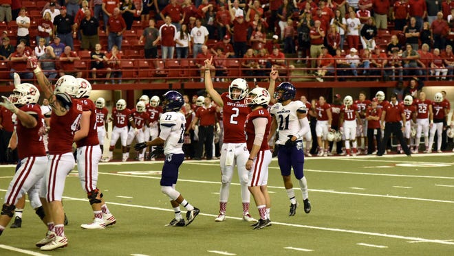 South Dakota players raise their arms in victory after defeating Weber State on an overtime field goal in 2016 at the DakotaDome.