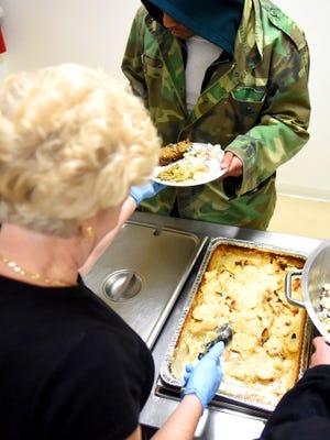 A volunteer hands over a hot plate of food to a homeless individual spending the night at WARM which operates out of the Fishersville United Methodist Church on Friday, March 27, 2015. WARM is a network of churches operating a night refuge for the Valley's homeless during the coldest winter months. 