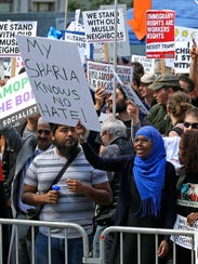 A woman holds a sign that reads "My Sharia Knows No