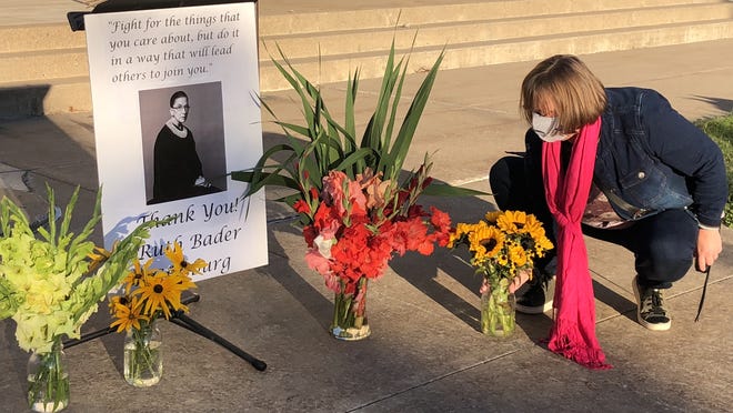Ruth Bader Ginsburg vigil organizer Cyndi Forham places flowers around the late Supreme Court justice's photo Sunday.