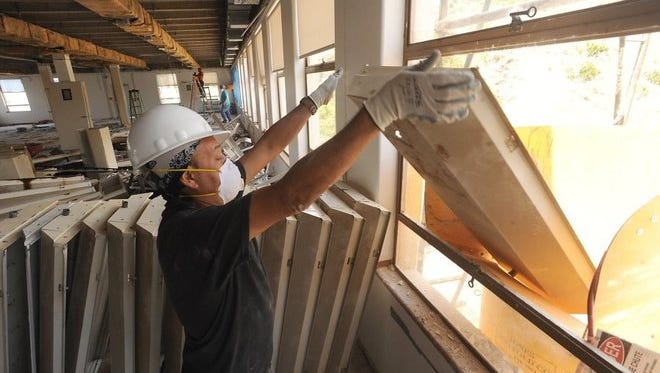 Ruben Aviles sends a light panel down a garbage chute as he and others remodel the fifth floor of Ventura City Hall North in June.