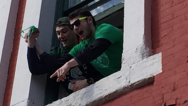(Left to right) Connor TenEyck and Joey Bitetto reach outside a window to catch beads.