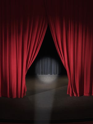 Empty stage with curtains slightly open and spotlight on