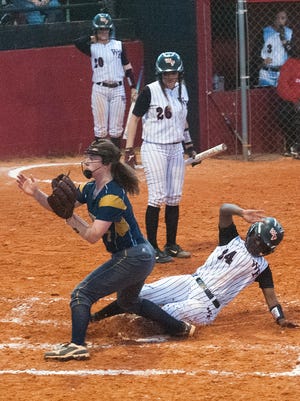West Florida High School's Keyana Norman, (No. 24) scores on a pass ball as Gulf Breeze High School's Amanda Klemm, (No. 7) tries to make the play at the plate during Tuesday night's Region 1-6A championship game.