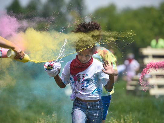 Students run through clouds of colored powder during